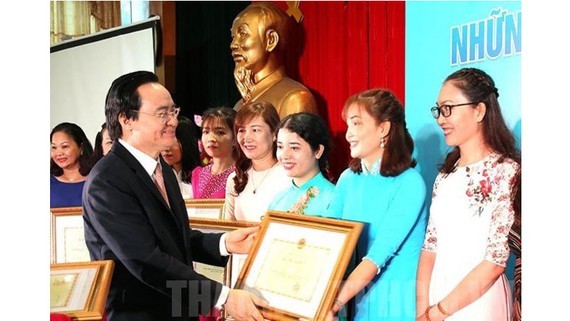 Minister Nha gives certificates of merit to outstanding teachers at the ceremony (Photo: SGGP)