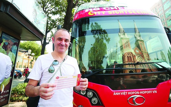 A foreign tourist buys a fare for hop-on hop-off tour in HCMC (Photo: SGGP)