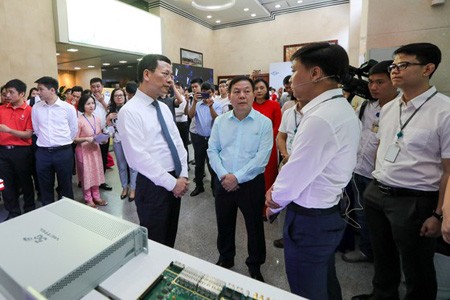 Minister of Information and Communications Nguyen Manh Hung paid a tour to ‘Make in Vietnam’ technological products in an exhibition in the framework of the conference. (Photo: SGGP)