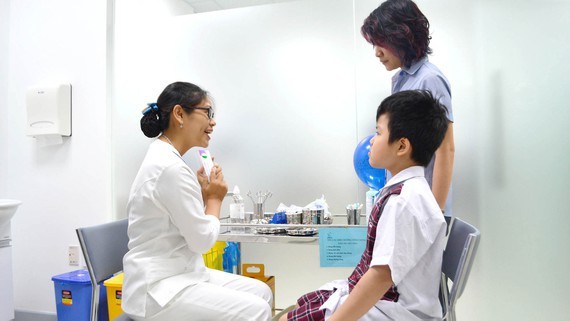 A medical worker is explaining the benefit of vaccination to a boy before administering a vaccine shoot (Photo: SGGP)