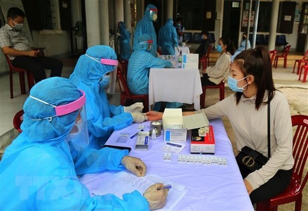 Medical workers conduct quick tests for people returning from COVID-19-hit regions (Photo: VNA)