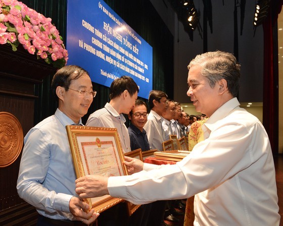 Deputy Chairman of the city People's Committee Ngo Minh Chau presents certificates of merit to administrators in districts which carried out good administrative reform programs (Photo: SGGP)
