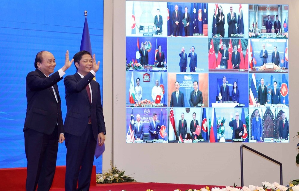 Vietnamese Prime Minister Nguyen Xuan Phuc (left) and Minister of Industry and Trade Tran Tuan Anh, together with leaders of other RCEP member countries, witness the pact signing via videoconference on November 15 (Photo: VNA)