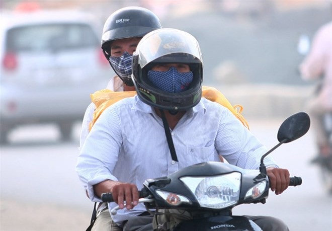 Motorbike riders in Hà Nội have to wear masks on a dusty highway section through Cau Dien - Nhon (Photo: VNA)