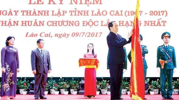 President Tran Dai Quang attaches the First class Independence Medal on traditional flag of Lao Cai province. 