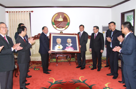  Deputy Standing Secretary of the Ho Chi Minh City Party Committee Tat Thanh Cang offers a portrait of Vietnamese President Ho Chi Minh and Lao President Cayson Phomvihan to Savannakhet province. (Photo:Ai Ch