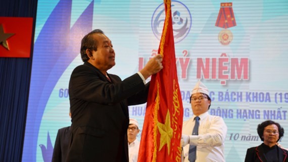 Deputy Standing Prime Minister Truong Hoa Binh offers the First Class Labor Medal of the Vietnamese President to the university's leaders.