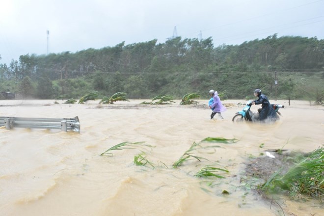 People wade through floodwater on Bridge 14, part of National Highway 26 in the Central Highlands province of Dak Lak, on November 4 morning, when storm Damrey hit the central coast (Photo: VNA)