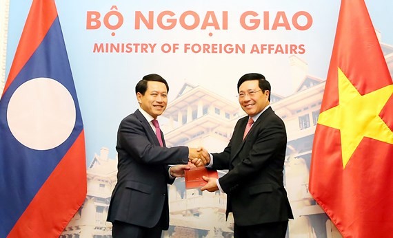 Vietnamese Minister of Foreign Affairs Pham Binh Minh and Lao Foreign Affairs Minister Saleumxay Kommasith exchange a protocol about the borderline and national border markers, an agreement on Vietnam-Laos border and border gate management regulations. (P