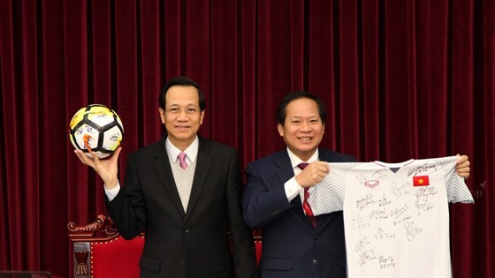 Minister of Labor - Invalids and Social Affairs Dao Ngoc Dung (left) and Minister of Information and Communications Truong Minh Tuan receive ball & football shirt of Vietnam U23 team offered to Prime Minister for auction.