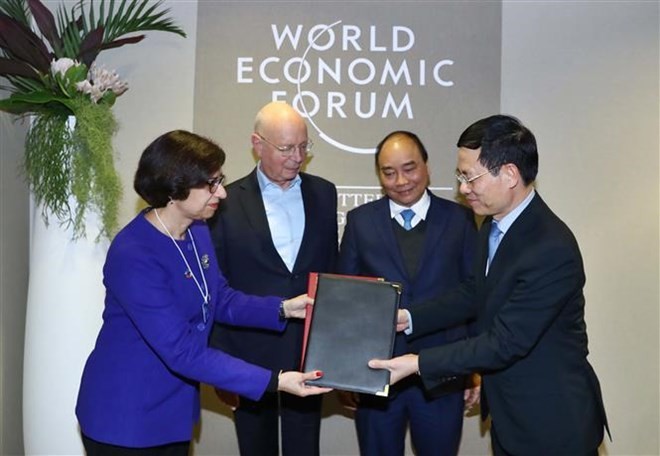 PM Nguyen Xuan Phuc (blue tie) and WEF Founder and Executive Chairman Klaus Schwab witness the signing of  an agreement between the WEF and Vietnam on building a centre for the Fourth Industrial Revolution. (Photo: VNA)