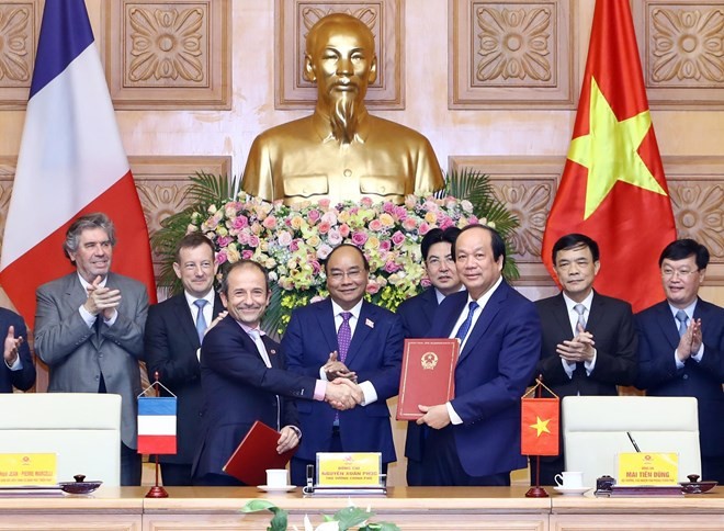 Prime Minister Nguyen Xuan Phuc (C) witnesses the signing ceremony between the Government Office of Vietnam and the French Development Agency (AFD) in e-government development cooperation (Photo: VNA)