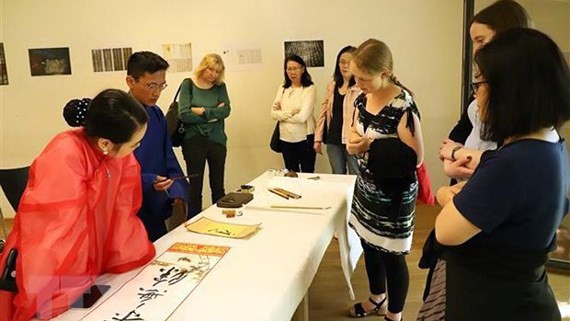 German and foreign tourists experience calligraphy performance at Vietnam Tag