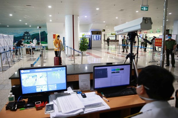 A staff member at Noi Bai International Airport in Hanoi checks passengers' body temperature via a thermal scanner (Photo: VNA) 