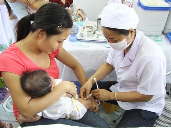 Nhân viên y tế tiêm vaccine TCMR cho trẻ
