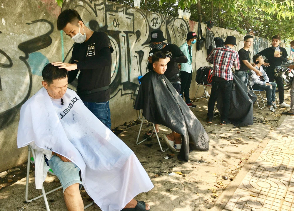 Tiệm cắt tóc miễn phí trên vỉa hè đường Phạm Văn Đồng