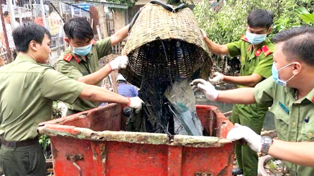 Cán bộ - chiến sĩ trẻ Công an quận 8 tham gia dọn rác trên rạch trong chiến dịch Hành quân xanh 2018. Ảnh: TUẤN VŨ
