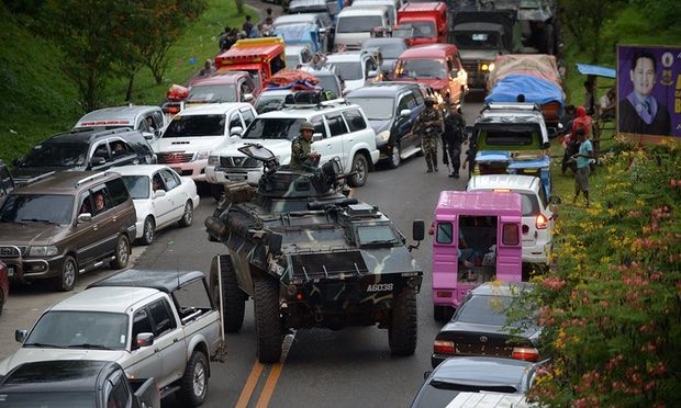 圖為一輛裝甲運兵車和逃離馬拉維市的居民車輛。（圖源：Getty Images）