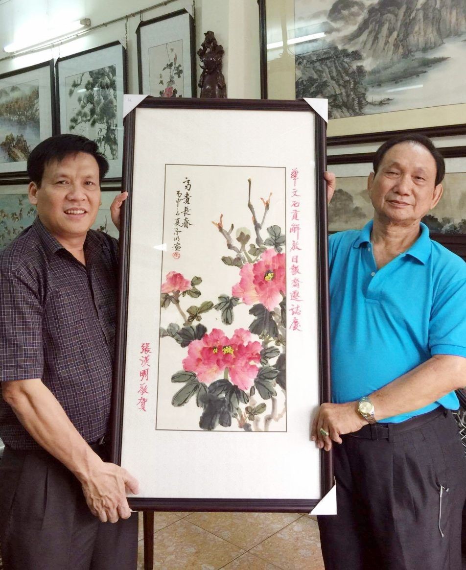 阮玉英主編（左）接受張漢明書畫家贈送畫作。