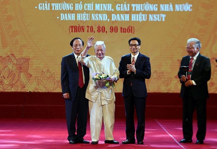 政府副總理武德膽（右二）向人民藝人、教授陳榜贈送鮮花祝賀。（圖源：廷南）