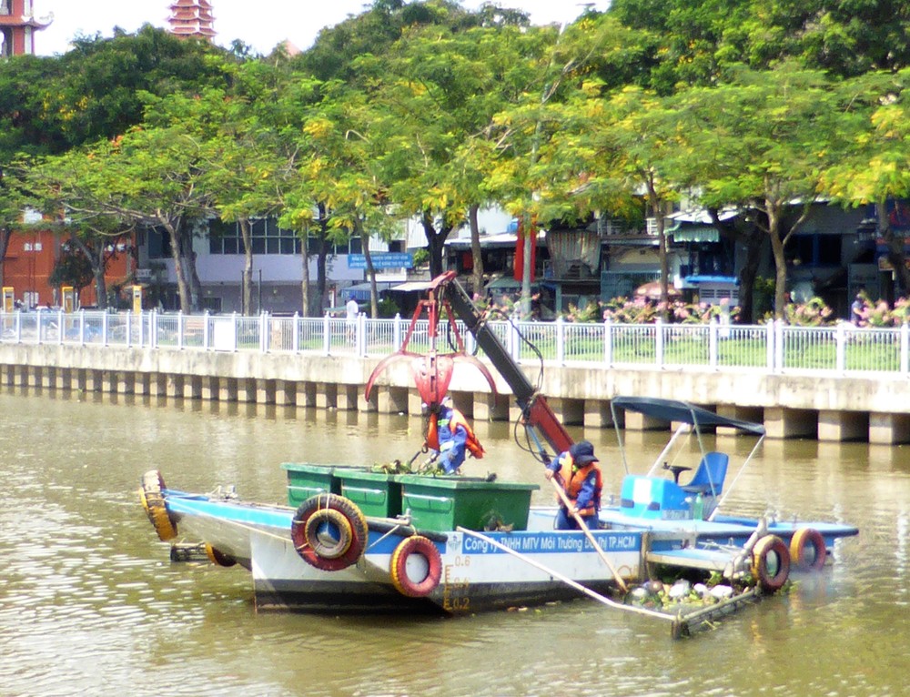 市都市環境公司清潔員採用特製浮船在饒祿-氏藝涌上穿梭打撈水面漂浮物垃圾。