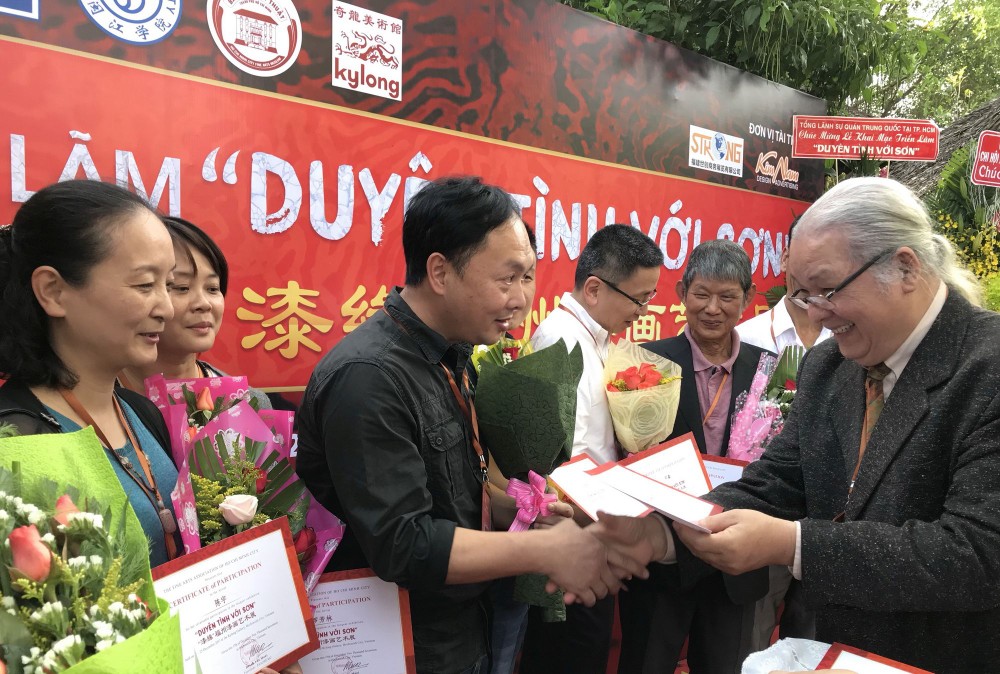 市美協主席黃文梅向越中參展畫家頒發證書。