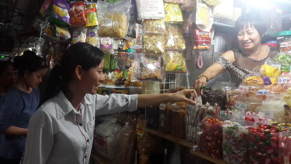 平西市場華人商販向顧客介紹蜜餞。