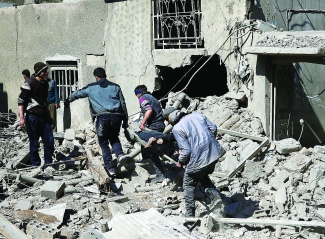 敘利亞東古塔地區遭轟炸，民眾從瓦礫中抬走一具屍體。（圖源：路透社）