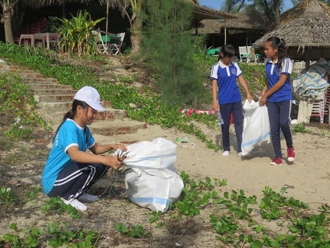 響應"綠色星期天”活動，學生們在沙灘上撿垃圾護海洋。（圖源：越通社）