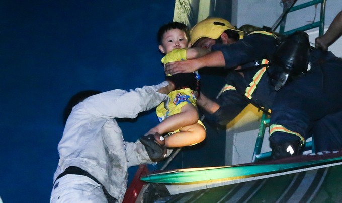 消防員搶救一名兒童離開火警現場。
