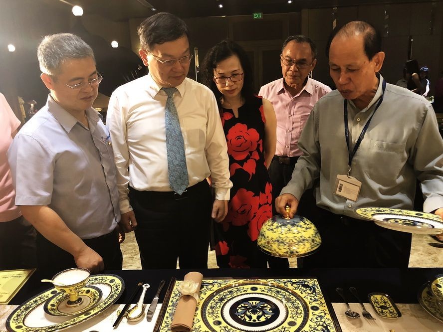 李玉明先生(右一)向到訪賓客介紹 2017年越南舉辦亞太經合會議國宴上明隆一生產的餐具。
