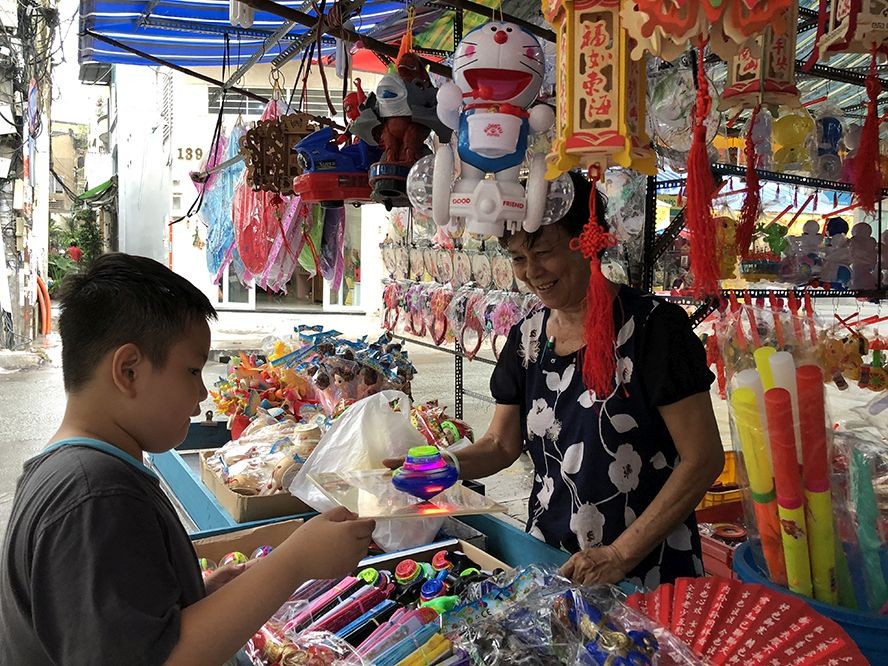 在第五郡傳統花燈街的華人商販向小朋友介紹新款花燈。