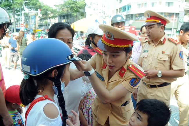女交警向一名小學生贈送達標安全帽並指引正確的戴法。