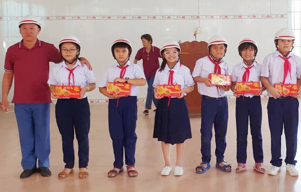 鄭成龍理事長向兒童贈送月餅及安全帽。