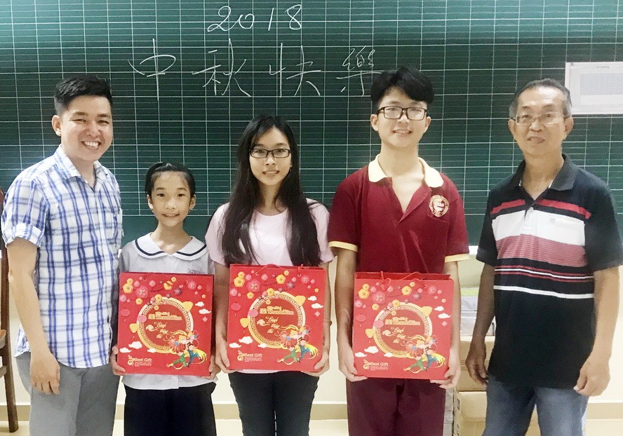 崇華華文中心校政主任徐永華老師（右一）和曾廣健老師向各學生贈送月餅。