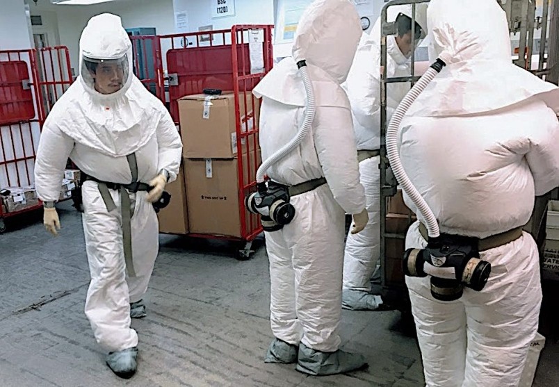 穿著生化防護衣人員2日在國防部郵件處理中心過濾郵件和包裹。（圖源：AFP）