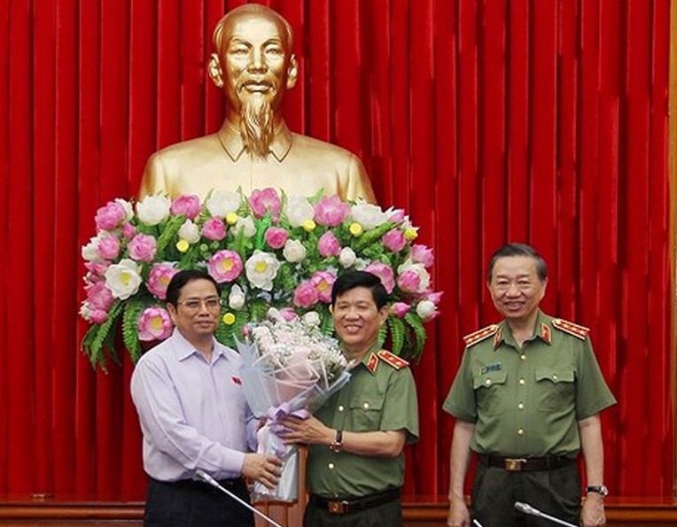 中央組織部長范明政（左）向公安部副部長阮文山中將（中）送鮮花表示祝賀。（圖源：春春）