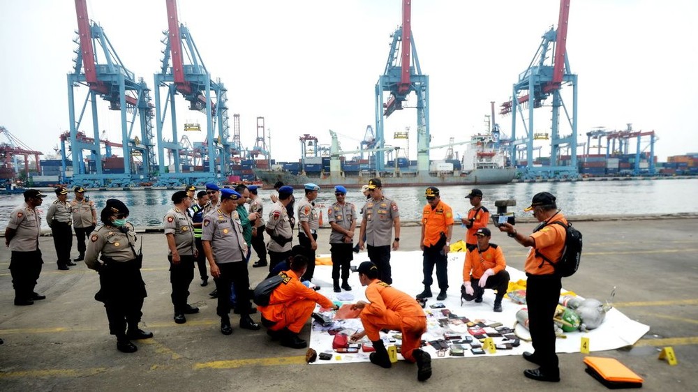 10月30日，在印度尼西亞雅加達戈戎不碌港口，印尼警方與國家搜救局工作人員查看失事客機乘客的個人物品。（圖源：新華網）