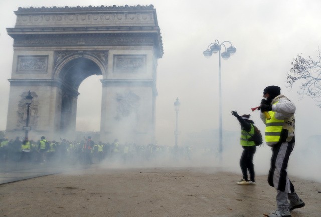 法國巴黎「黃背心」示威與警方爆發衝突，警方使出催淚瓦斯和震撼彈，圖中凱旋門被煙霧壟罩。（圖源：AP）