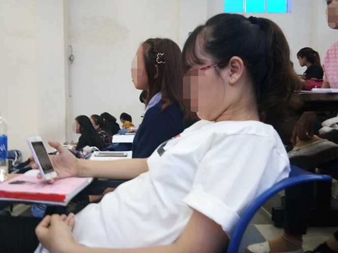 某學生在上課時只顧看手機而不專心聽老師講解。
