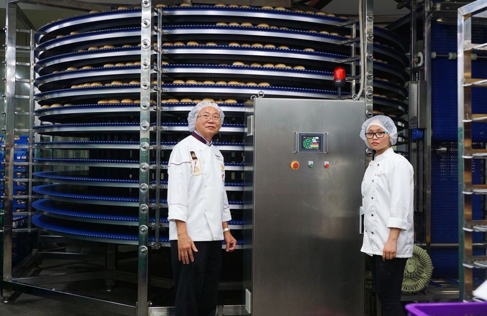 亞洲餅家總經理高肇力(左)視察全自動設備的生產情況。
