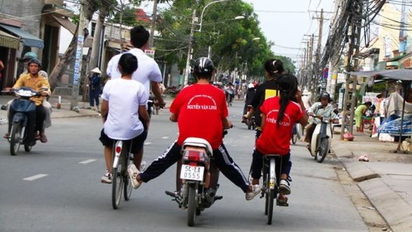 一輛摩托車推著２輛自行車在街上並排駕駛的情景要不得。