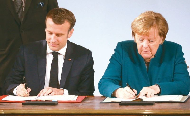德國總理默克爾（右）和法國總統馬克龍（左）當地時間22日在德國西部城市亞琛簽署《德國和法國關於合作和一體化的條約》(《亞琛條約》)。（圖源：AFP）