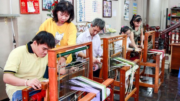 阮氏清水老師（左二）和胡氏金釵老師（右邊）在給學員們指導紡織方法。
