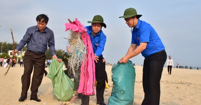 穿綠色志願青年制服和戴漁夫帽的潘玉壽同志（中）步入順安海灘打掃，清理垃圾。（圖源：明晰）