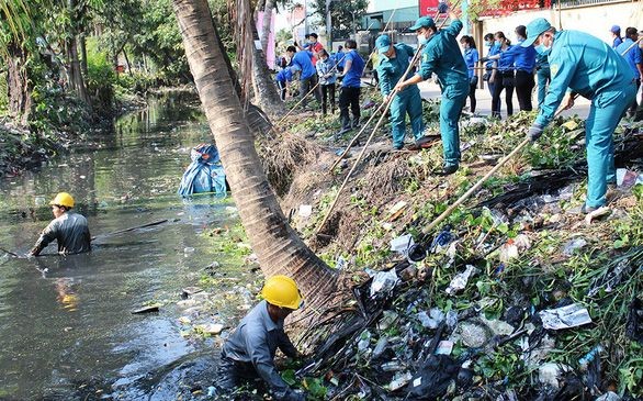 本市年輕人與都市排水人員配合清理第十二郡盛祿坊黏土渠上的垃圾。