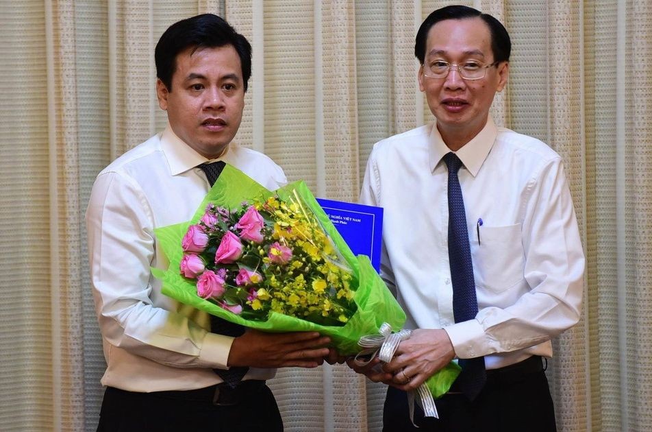 新任市計劃與投資廳副廳長陳英俊（左）從市人委會常務副主席黎清廉手中接過人事委任《決定》和祝賀鮮花。（圖源：光定）