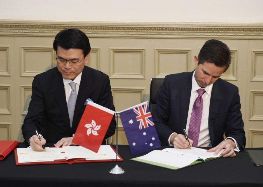 邱騰華在澳洲悉尼與澳洲貿易、旅遊和投資部長伯明翰（右）簽署香港與澳洲《自由貿易協定》和《投資協定》。（圖源：香港政府新聞網）