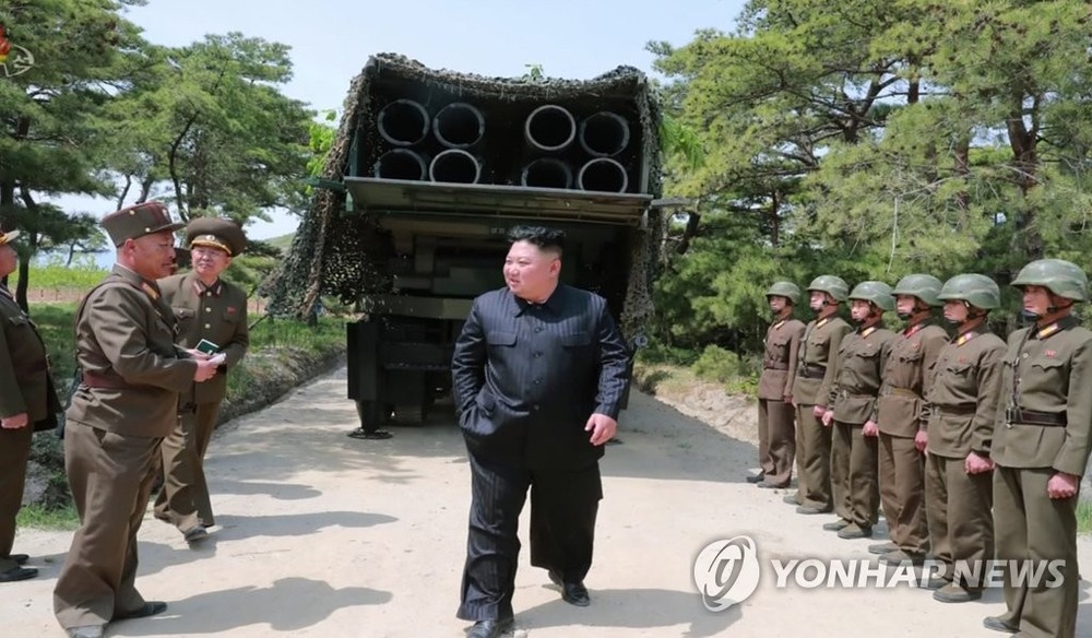 圖為朝鮮國務委員會委員長金正恩（居中）以300毫米口徑放射砲為背景向朝軍官兵下達指示。（圖源：韓聯社）