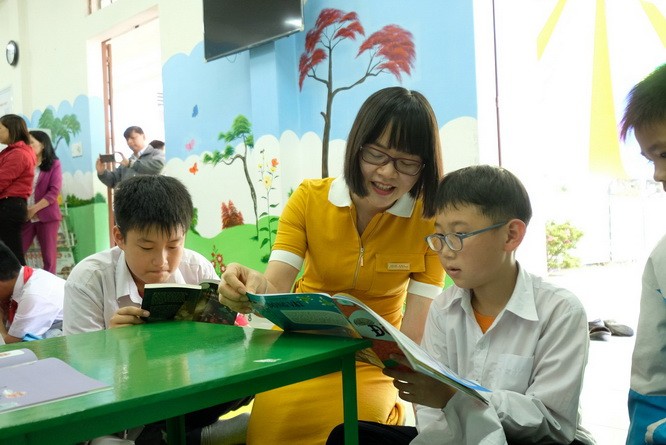 安平銀行副總經理阮氏香與小學生閱讀由該項目贈送的書本。